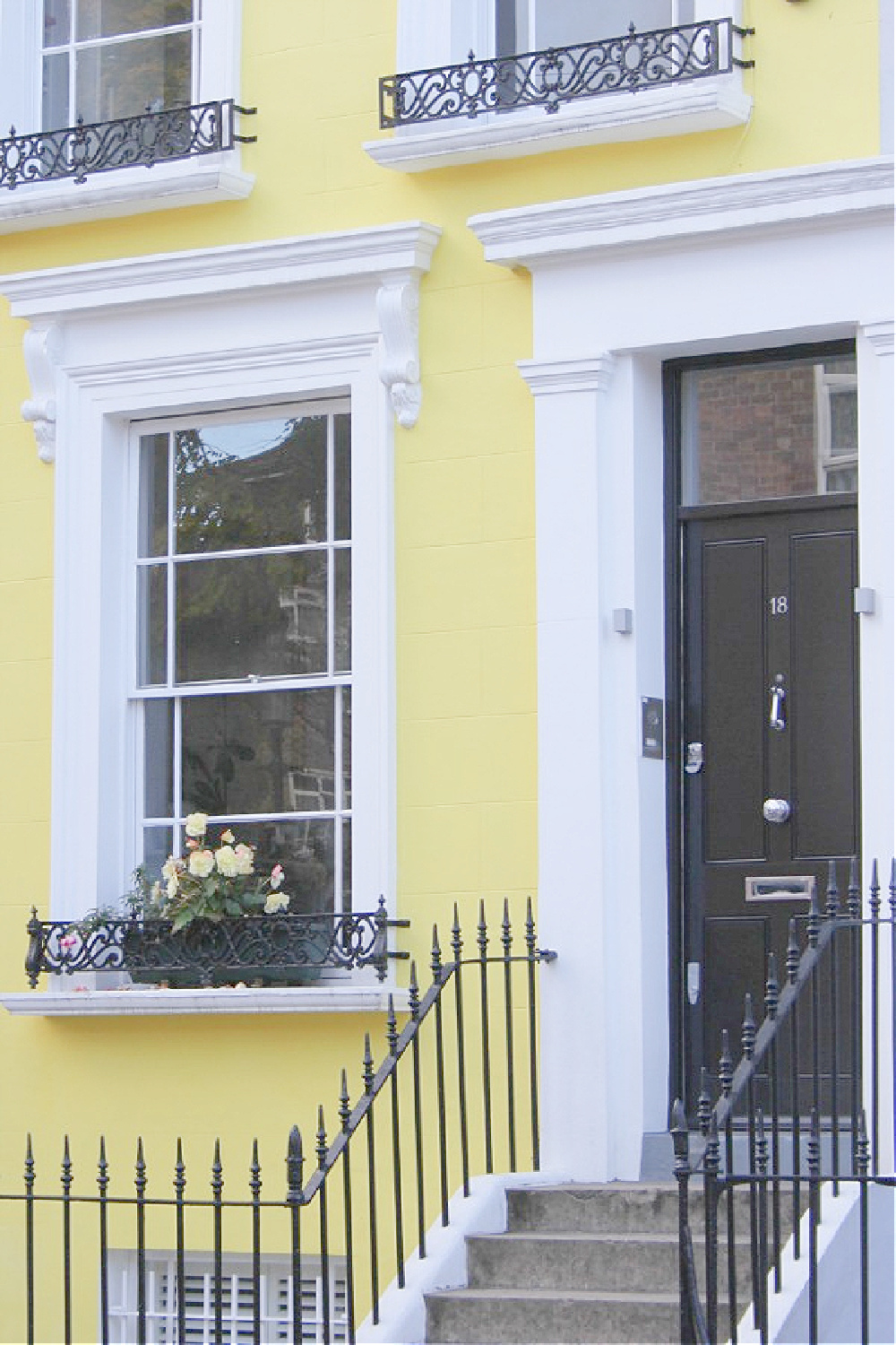 Gorgeous black door with white trim on vibrant yellow row house in Notting Hill. Come explore paint colors for your front door. #frontdoorcolors #paintcolors #curbappeal