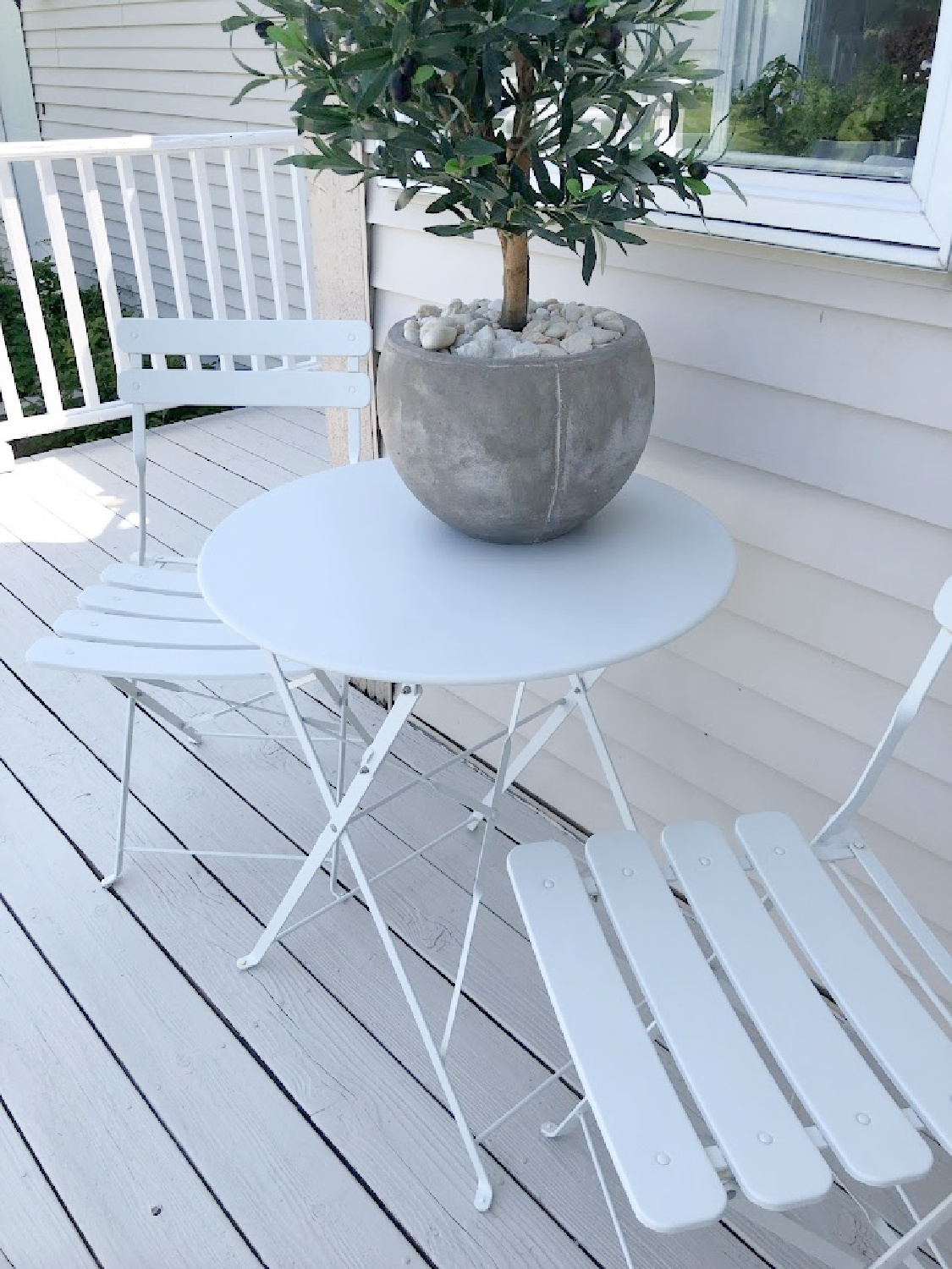 White bistro set on deck with stone/grey and white railing at the Georgian - Hello Lovely Studio.