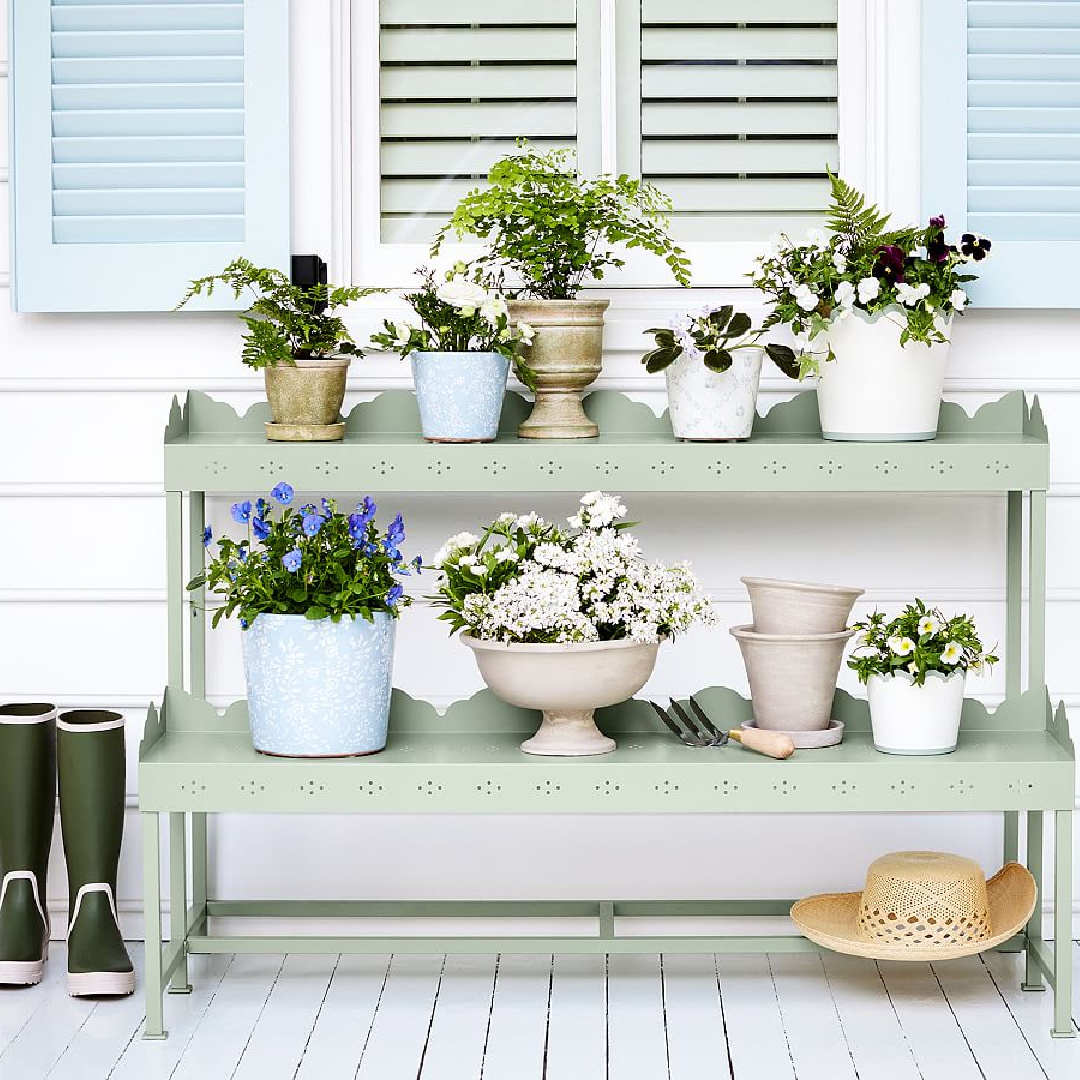 Sage green Julia Berolzheimer Fleur two Tier Scalloped Etagere from Pottery Barn with assorted potted plants on a porch. #plantstands #juliaberolzheimer #charlestonporch