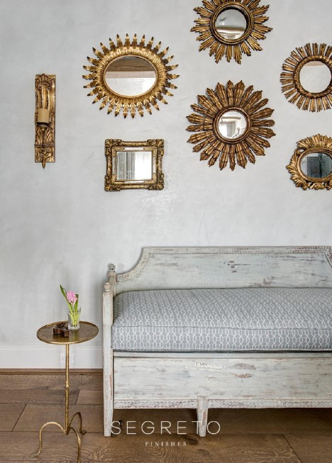 Sunburst mirrors massed on a plaster wall (Segreto Finishes) with antique bench. #oldworldstyle #plasterwalls