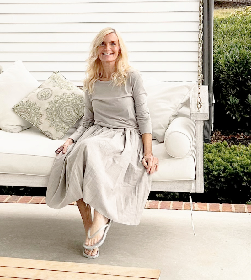 Michele of Hello Lovely Studio on porch swing wearing linen skirt and tee from Giannetti Home (Patina Home & Garden).