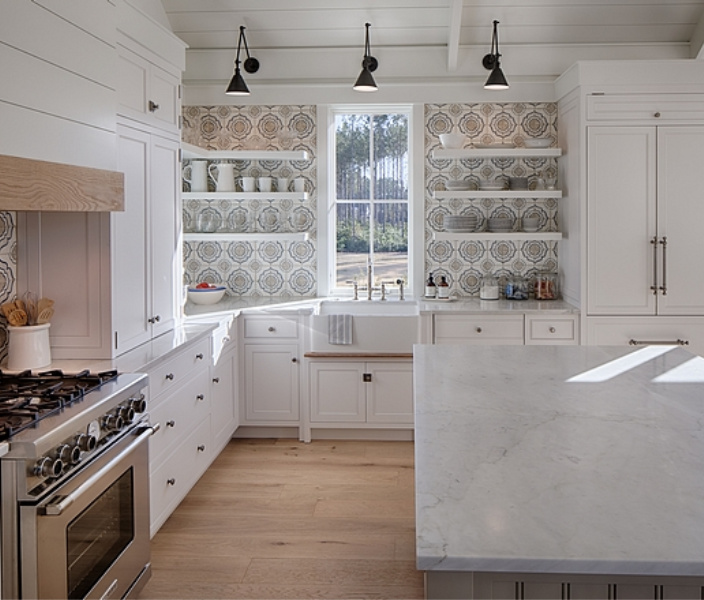 White coastal cottage kitchen with floating shelves, Shaker cabinets, white oak, and cement tile backsplash with blue accents. Lisa Furey. #coastalkitchen #whitekitchens #kitchendesign #modernfarmhouse #coastalcottage #cottagekitchen #floatingshelves #farmsink #shiplap