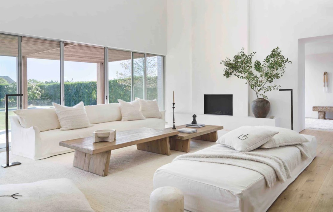 Warm, white modern relaxed living space with rustic wood low tables and minimal fireplace. Michael Del Piero (Richard Powers - photo) interior in TRAVELED AND TEXTURAL (Beta-Plus, 2023).