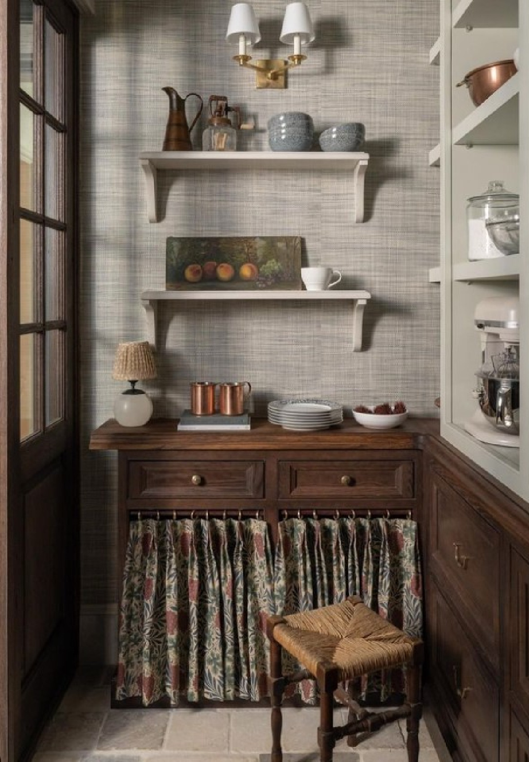 Whittney Parkinson designed pantry in Atlanta Whole Home 2023 with dark wood lowers, stone floors, grasscloth, painted shelves and skirted cabinet. Photo: Sarah Shields. #kitchenpantries #traditionalkitchens