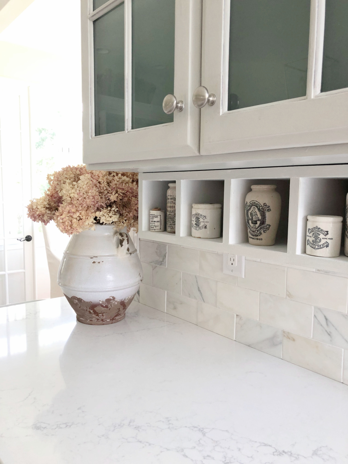 Serene white and light grey European country kitchen with Viatera Muse quartz counters, calacatta gold backsplash, and Pavilion Gray painted cabinets - Hello Lovely Studio. #eiderwhite #modernfrench #europeancountry #viateramuse