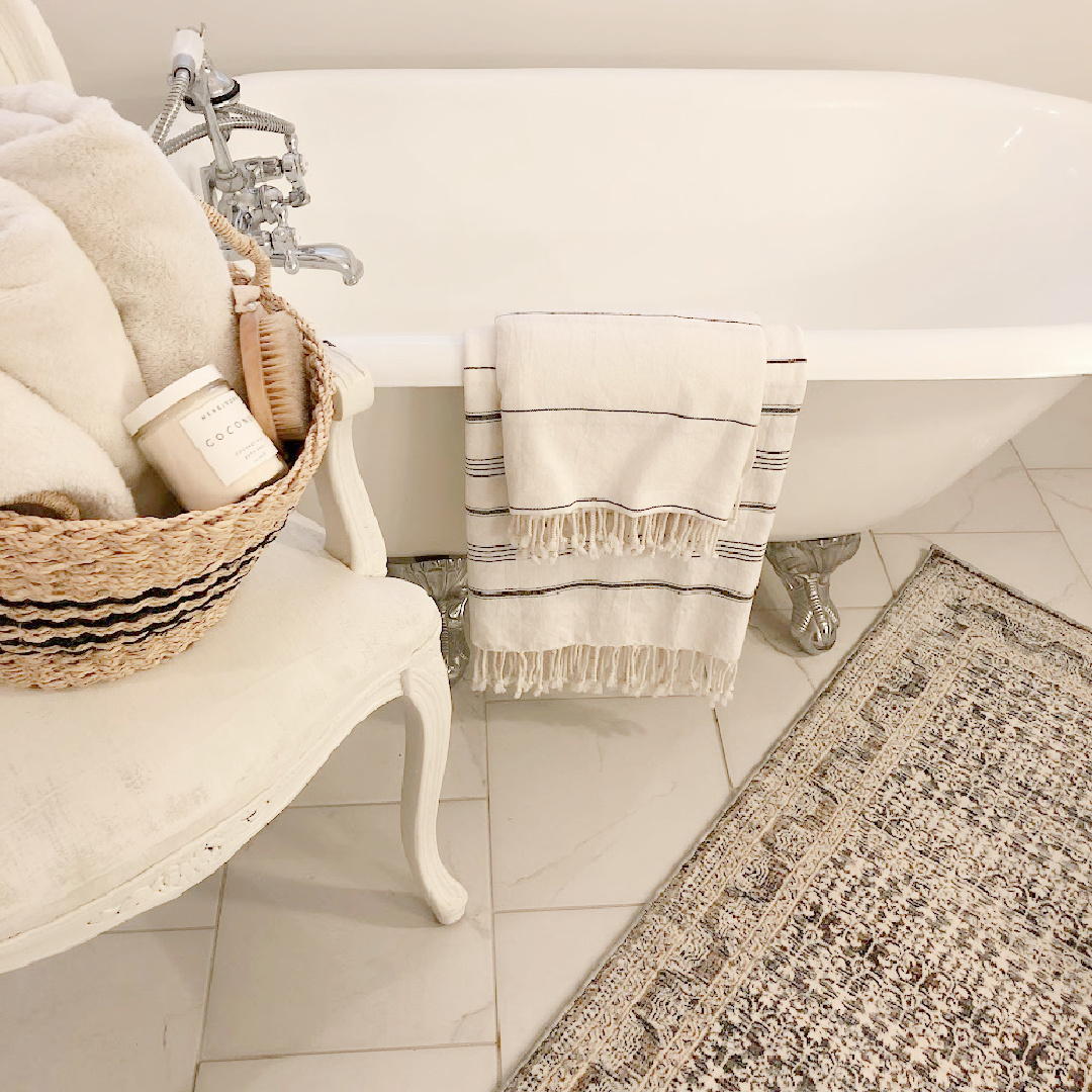 Hello Lovely vintage bath with clawfoot tub, Louis chair, and Zuma rug (Amber Lewis x Loloi).