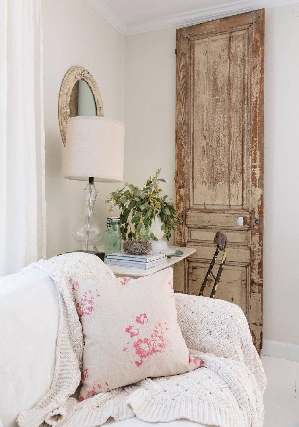 Rustic vintage wood door as an accent in a lovely white living room with Cabbages & Roses pillow. From Fifi O'Neill's SHADES OF WHITE (CICO, 2021). #fifioneill #vintagestyle