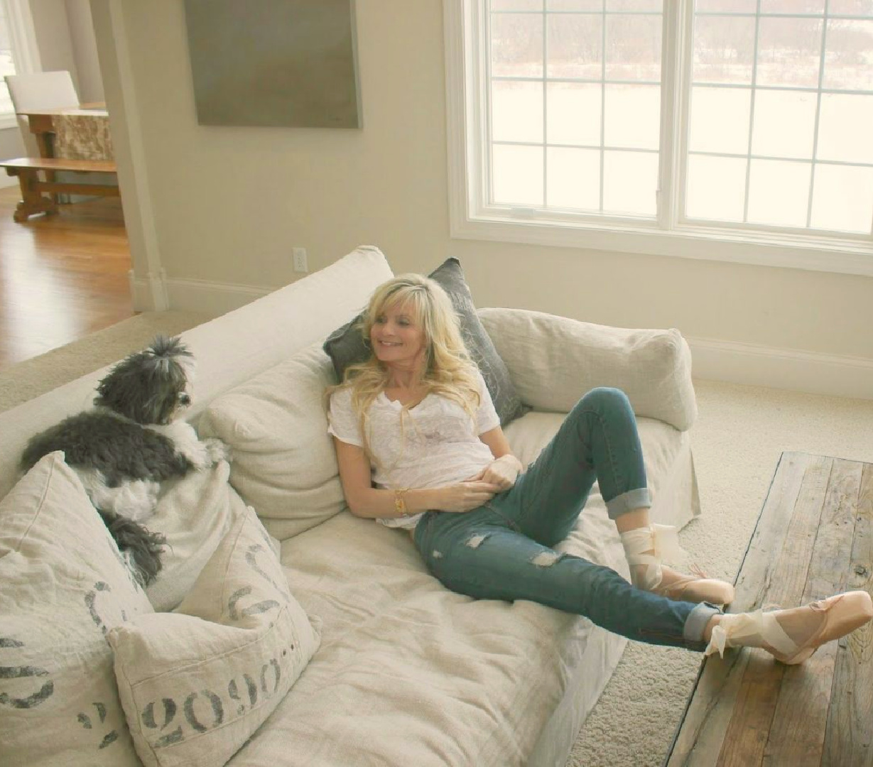 Benjamin Moore White Sand on walls in Belgian style living room with Michele and her black and white shihtzu - Hello Lovely Studio. #benjaminmoorewhitesand #belgianlinen