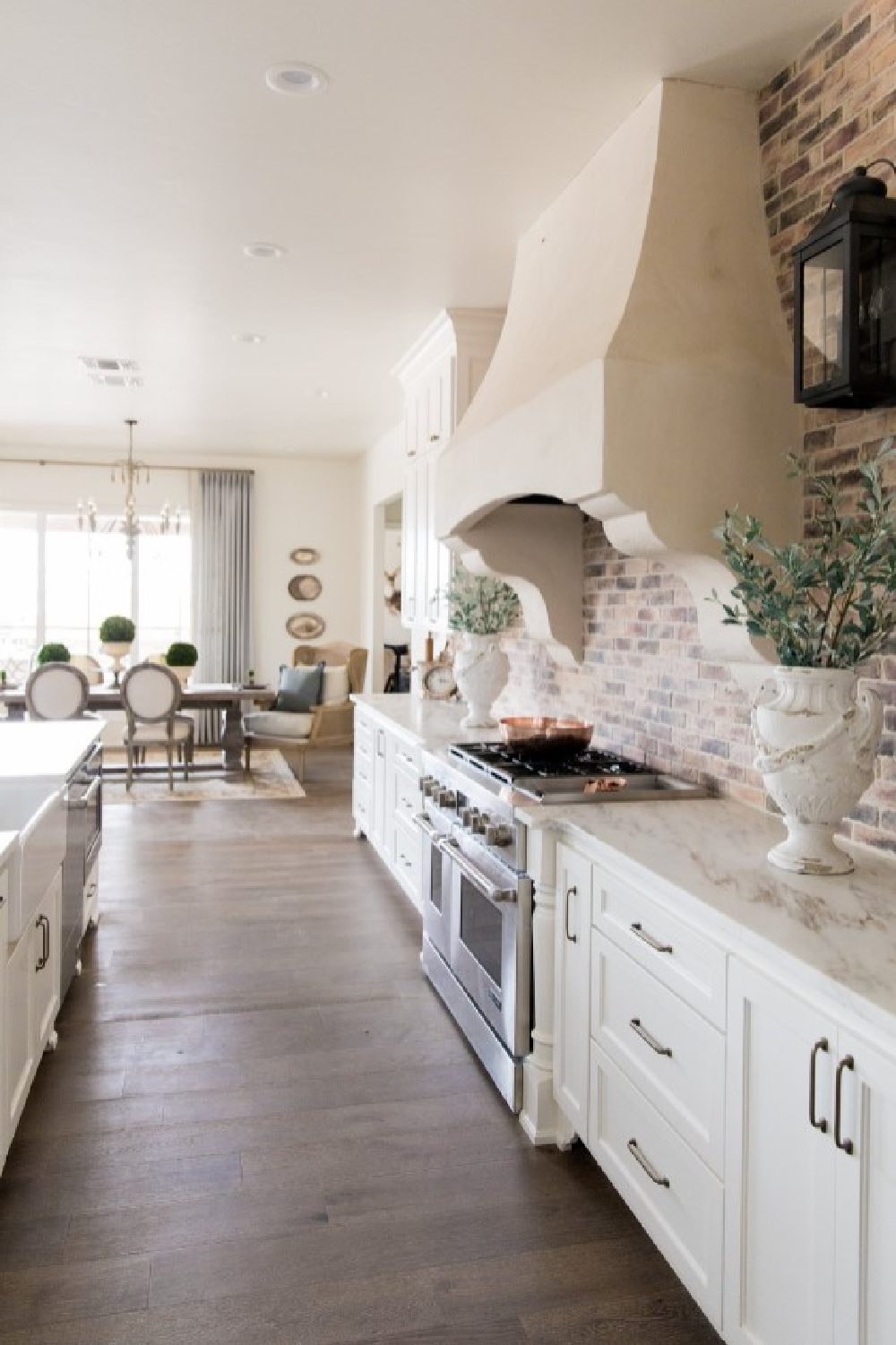 Sherwin-Williams Alabaster in a beautiful country French kitchen with Old World style and Chicago brick backsplash - design by Brit Jones. #swalabaster #modernfrench