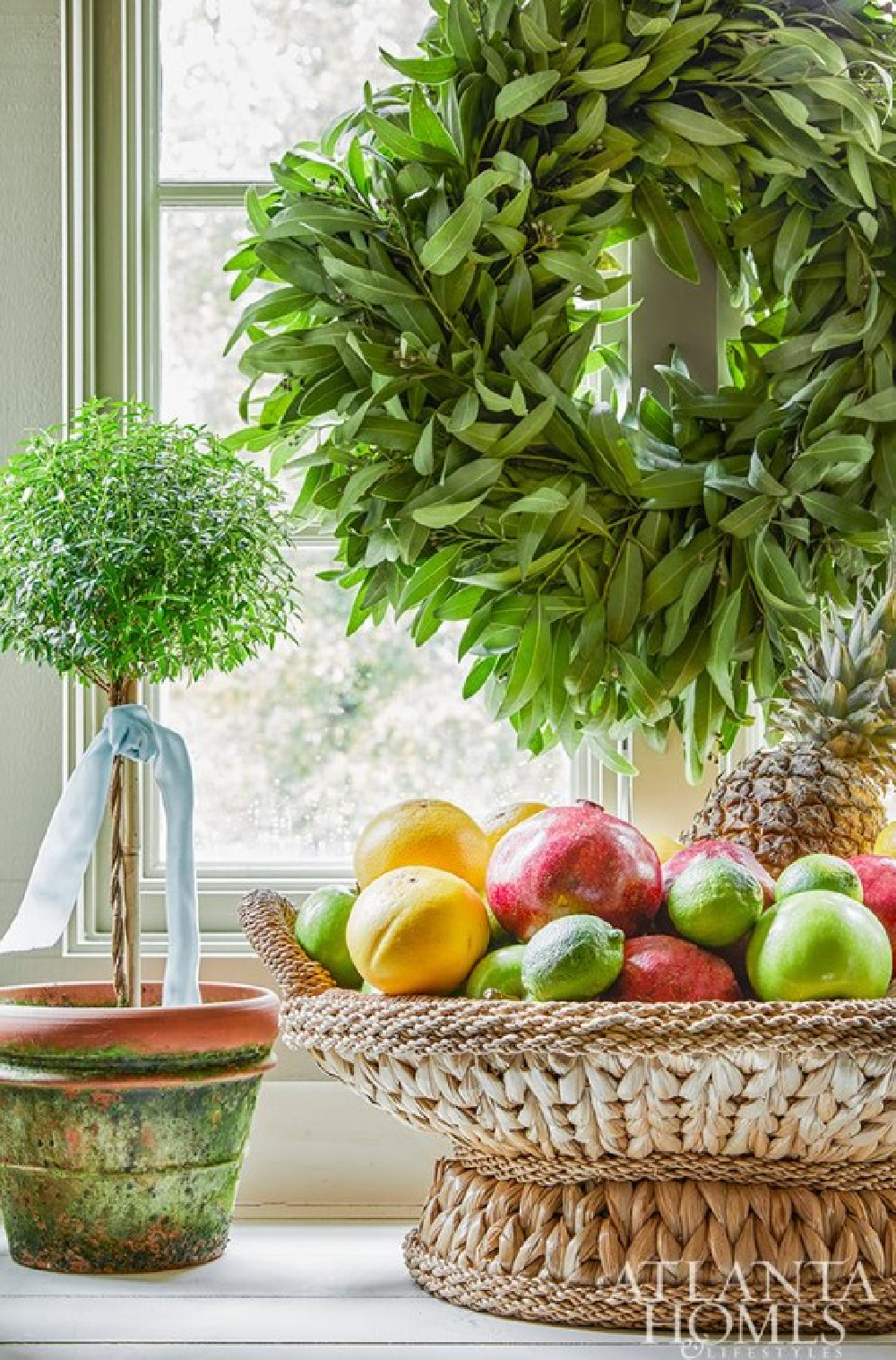 Southern Christmas decor from James Farmer in his Georgia cottage - here a topiary with a pale blue ribbon and woven basket filled with citrus feel naturally elegant and festive - Atlanta Homes. #southernchristmas #naturalchristmas