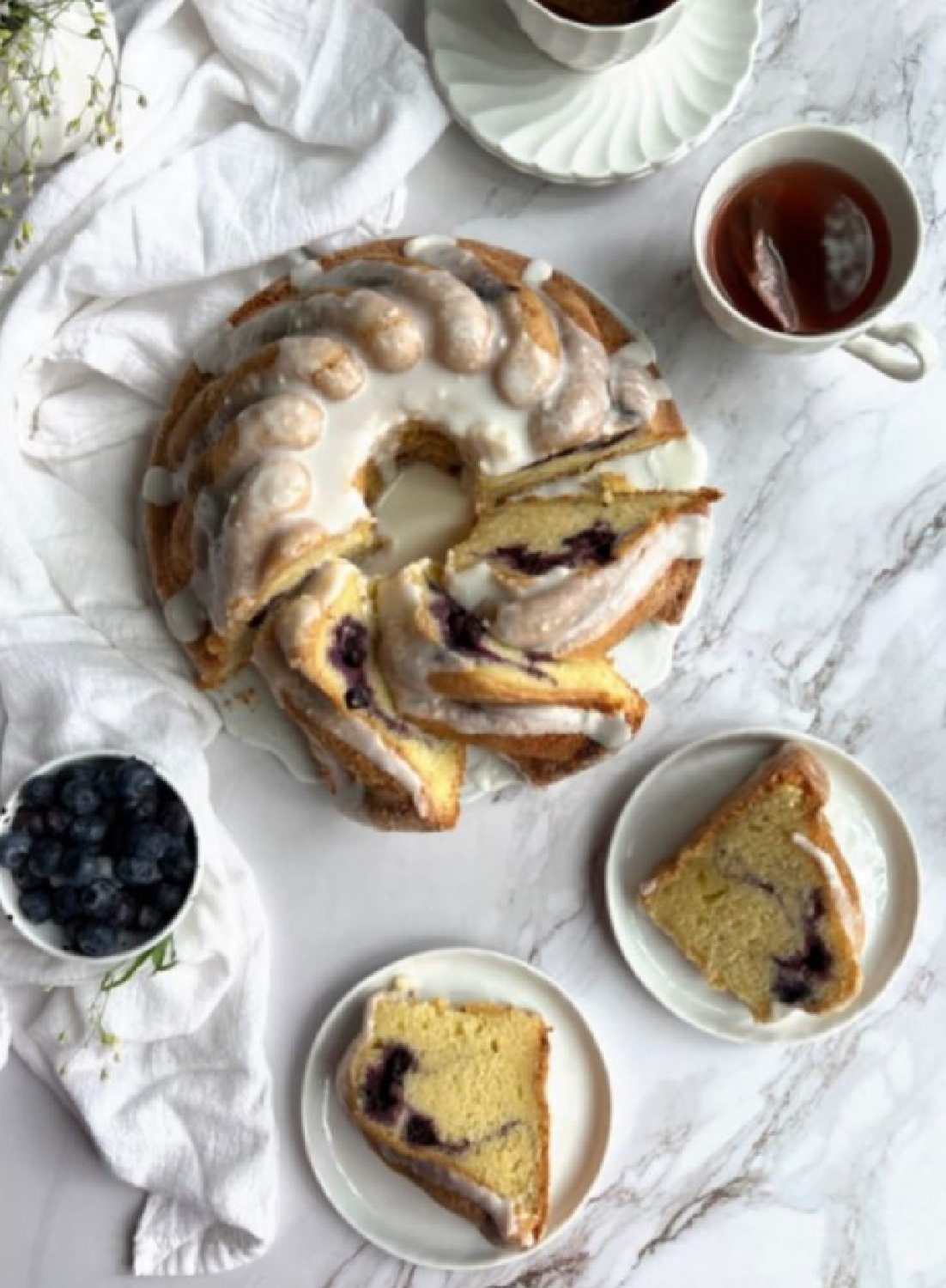 A lovely blueberry swirl bundt cake flatlay looks deliciously cozy for a fall brunch - Pinecones and Acorns. #blueberrycoffeecake #bundtcakes #fallcakes