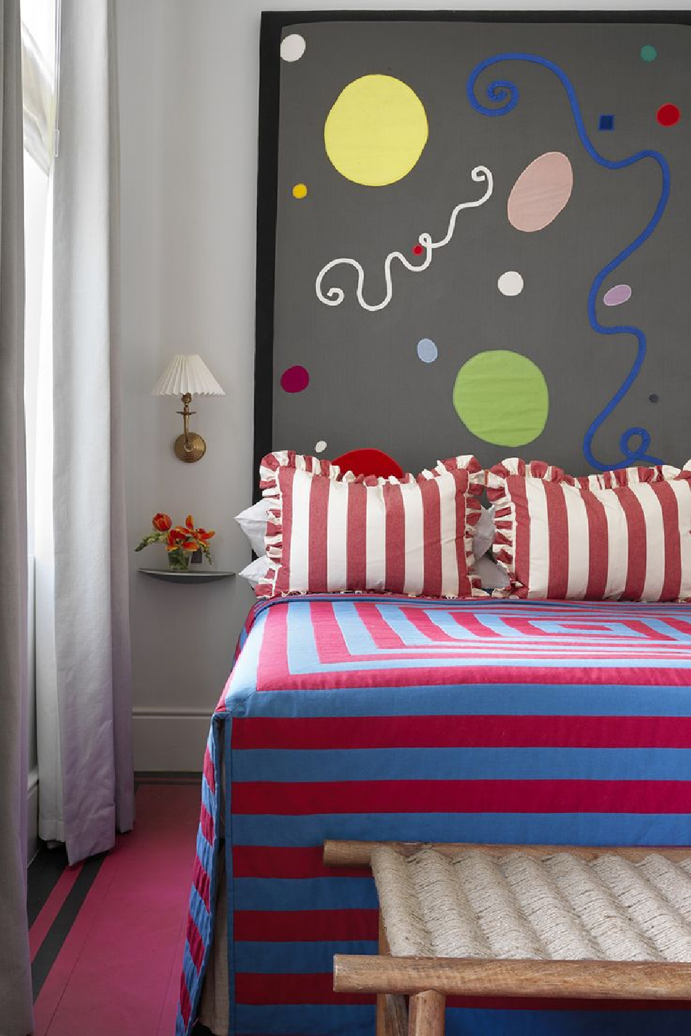 Whimsical bedroom with red stripe bedding and boldly modern headboard. Beata Heuman.
