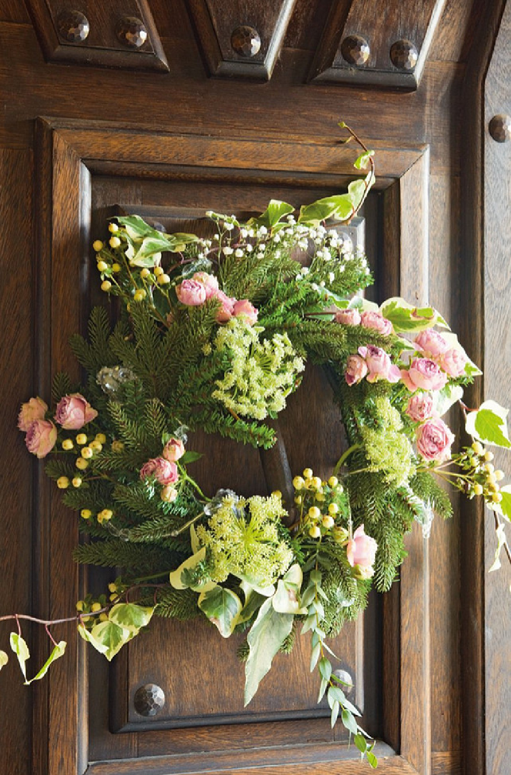Charming holiday wreath on door with pink flowers. El Mueble magazine. #frenchcountrychristmas #pinkchristmas #countryfrenchdecor #christmaswreath