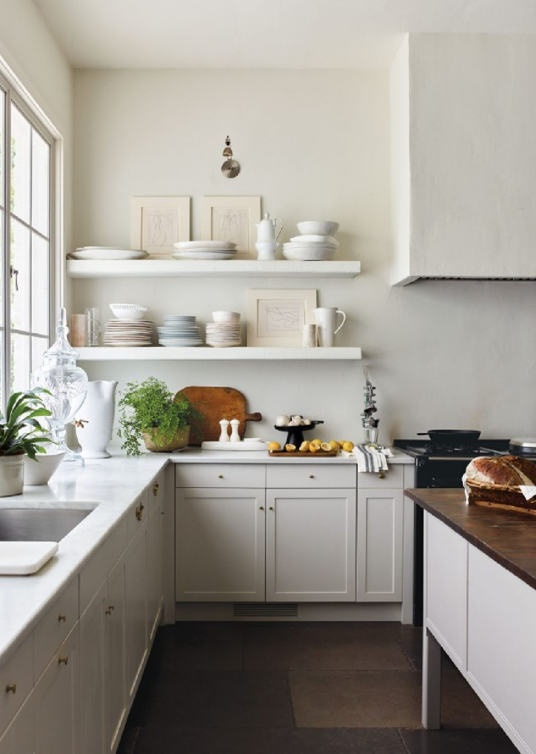 Serene white plaster in kitchen sets a quiet tone with open shelves and simple range hood. Architecture by D. Stanley Dixon with interiors by Carolyn Malone. #europeancountry #carolynmalone #stanleydixon #serenekitchens