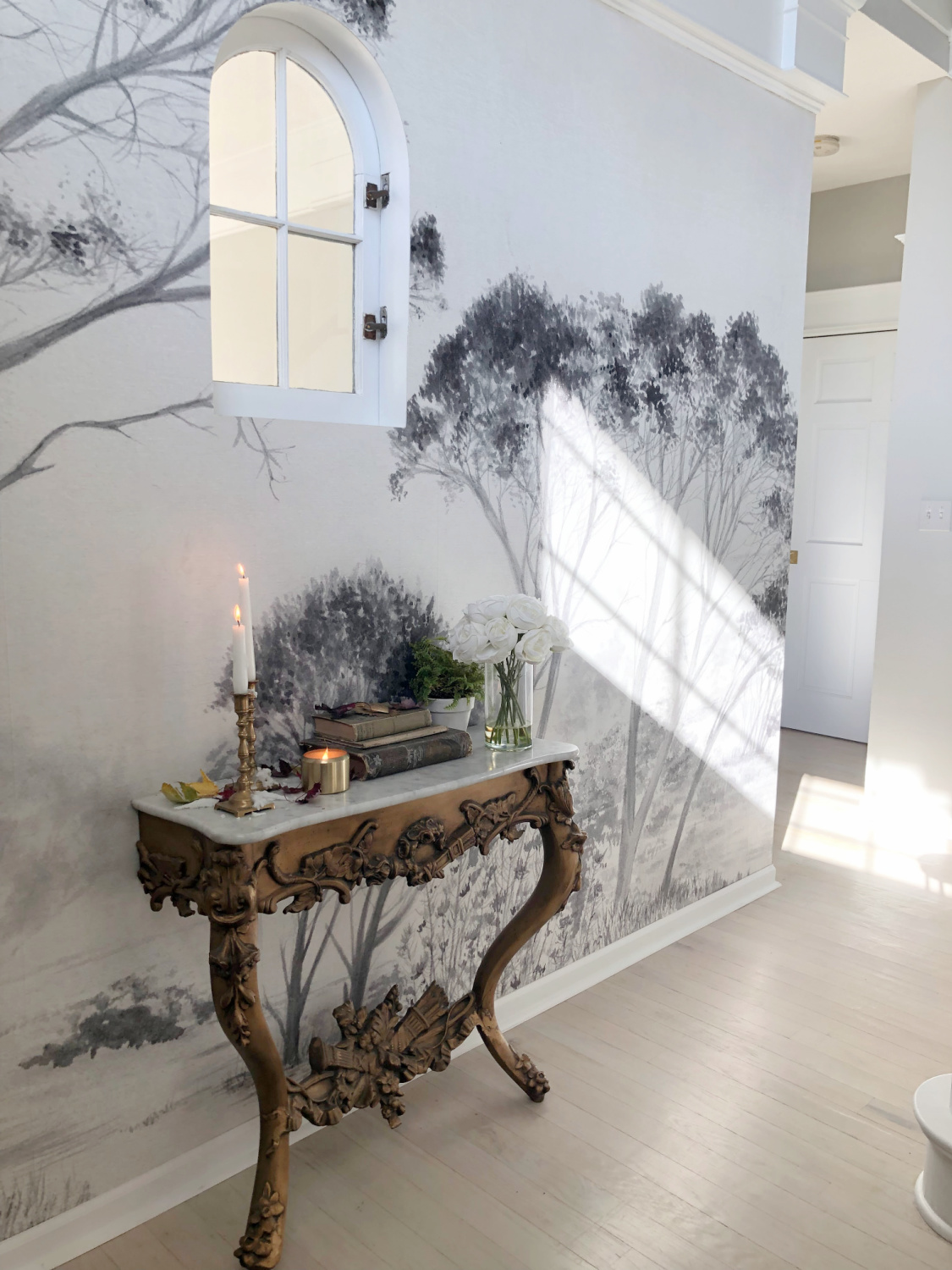 Hello Lovely's entry wallpaper mural with trees (Photowall) and French console with fall decor. #modernfrench #frenchconsole #treemural #grisaillemural