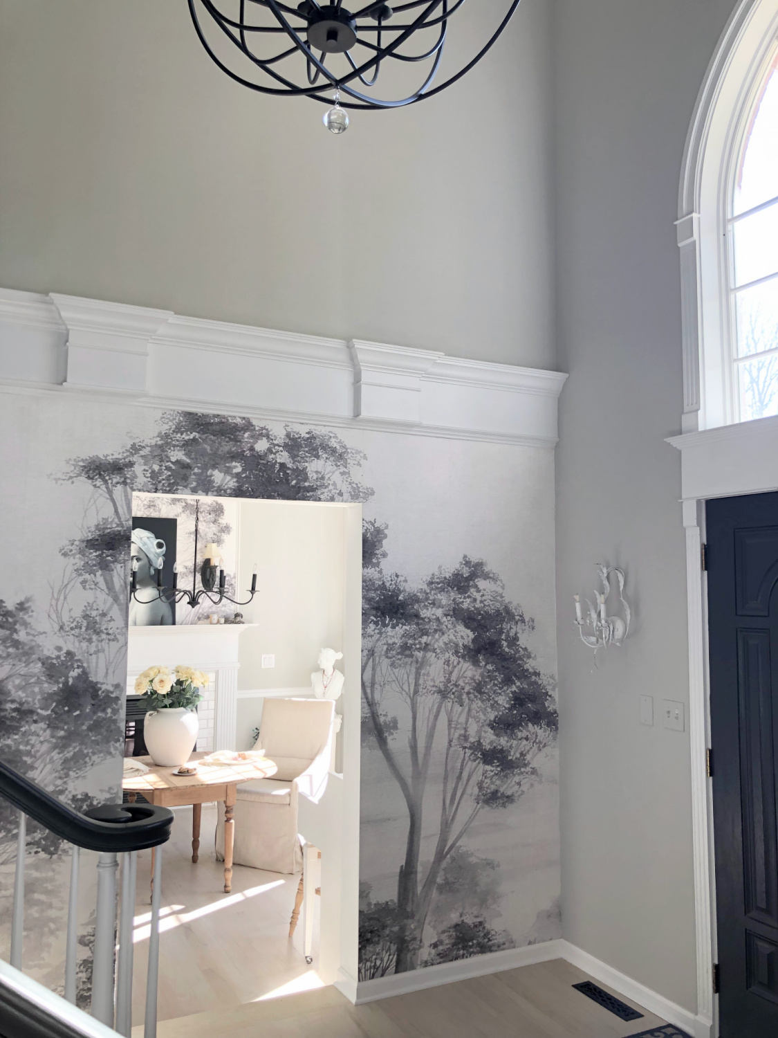 Hello Lovely's modern French entry with scenic tree mural wallpaper and serene dining room with fireplace.