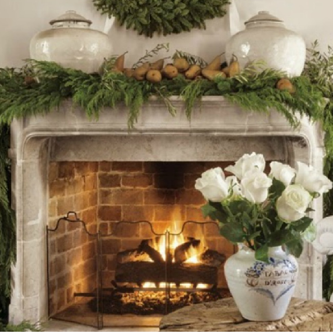 Pamela Pierce Christmas French carved stone fireplace. Mixed garland and olive branches gathered from yard, with ripe brown pears. Early Song dynasty jars anchor the scene with white roses. #pamelapierce #frenchchristmas #frenchcountrychristmas