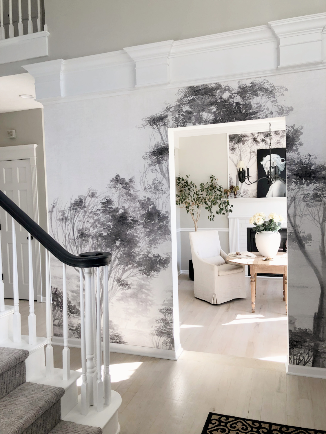 Hello Lovely's modern French entry with scenic tree mural wallpaper and serene dining room with fireplace.