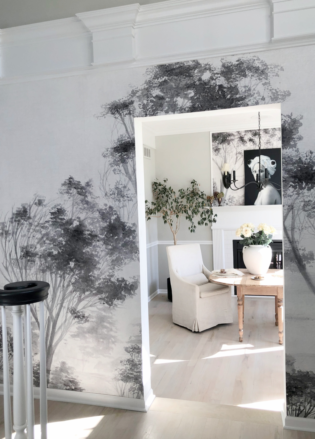 Hello Lovely's modern French entry with scenic tree mural wallpaper and serene dining room with fireplace.