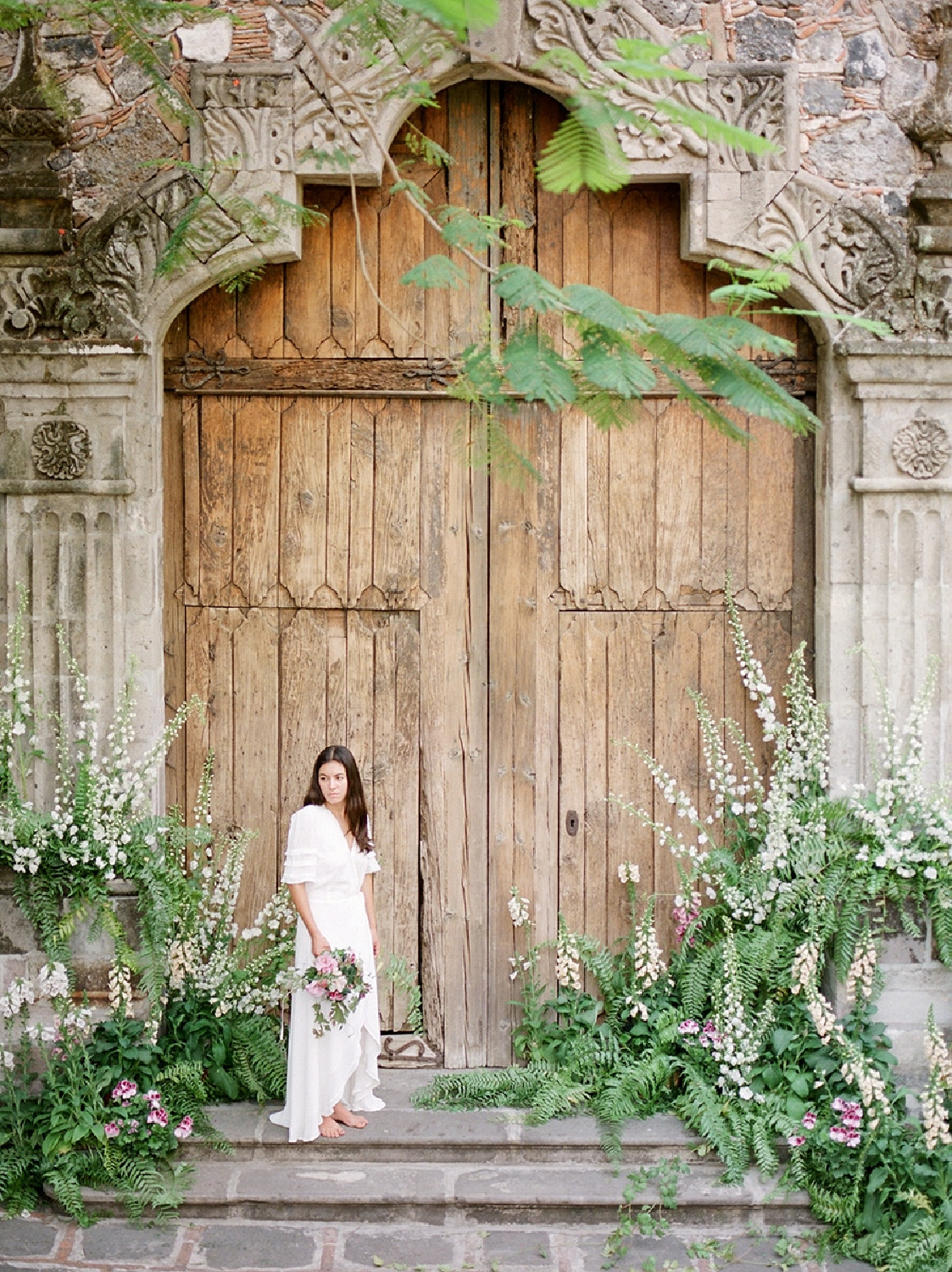 Hacienda Acamilpa's 17th century architecture and stunning wood doors are the backdrop for Sarah Winward's floral arrangements - photo: Heather Nan. #floralartistry #flowerarrangements #haciendaacamilpa