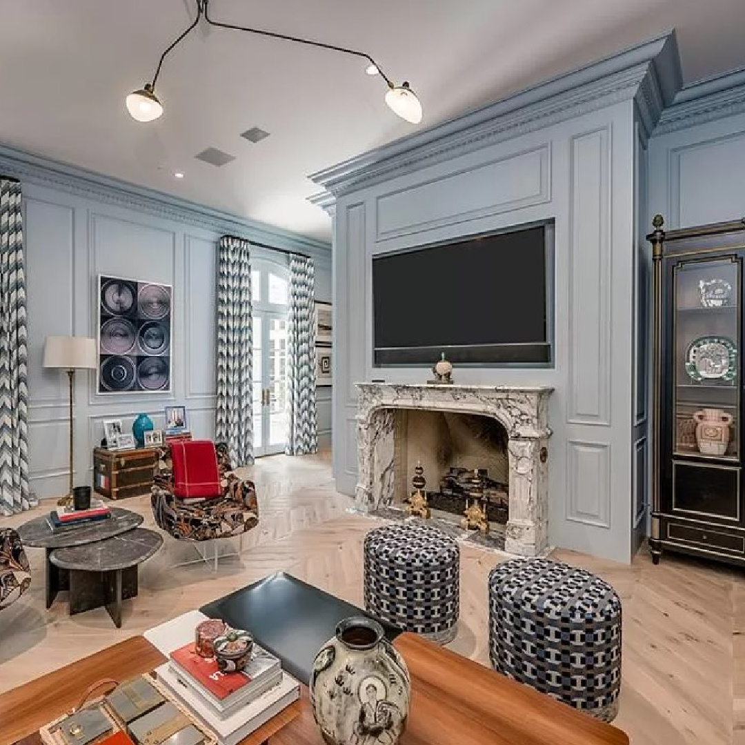 Blue walls with applied molding and modern light fixture in a media room of a luxurious chateau in Houston.