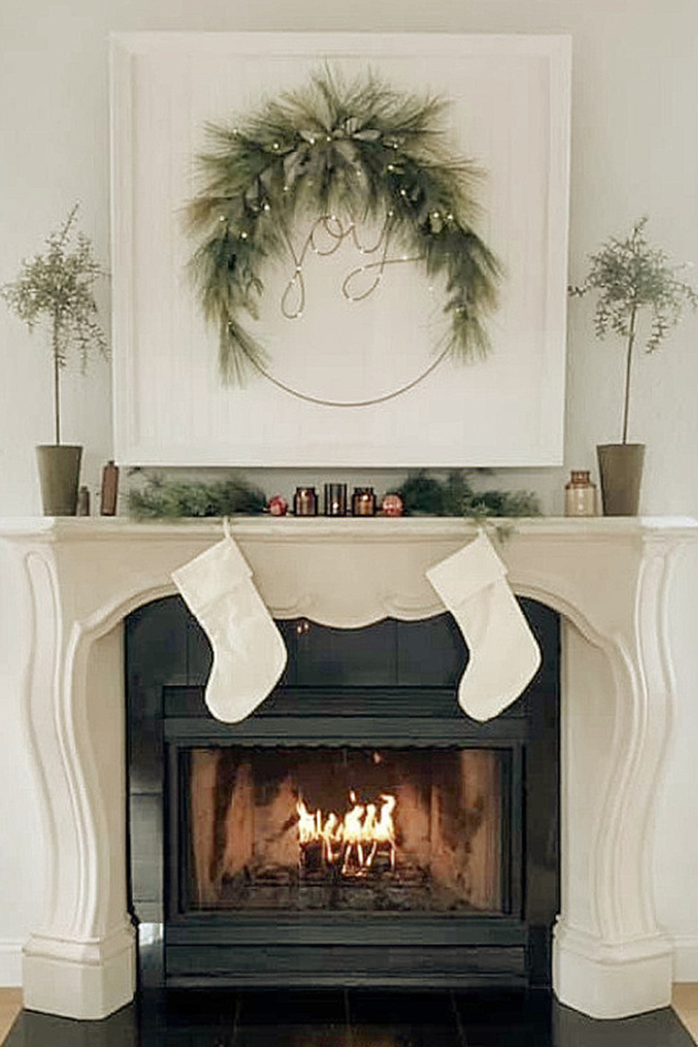 Christmas fireplace with joy wreath, stockings, and a French country surround - Hello Lovely Studio. #hellolovelychristmas #holidayfireplace