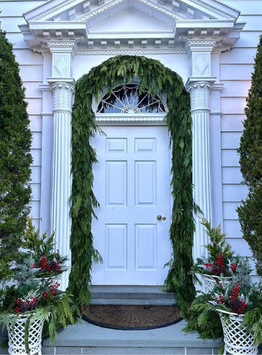 Breathtaking holiday porch and greenery on a home with classic architecture - @theenchantedhome. #christmasgarland #christmasporch