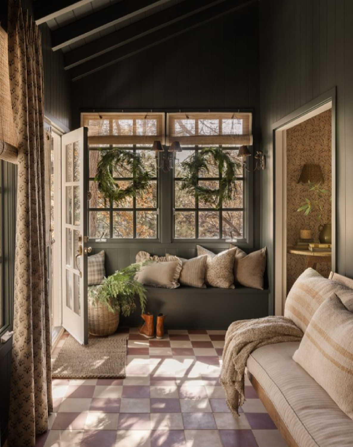 Amber Interiors designed holiday cozy porch with checkered floor and window seat. #europeancottage #warmcozyinteriors #rusticelegance #europeancountry