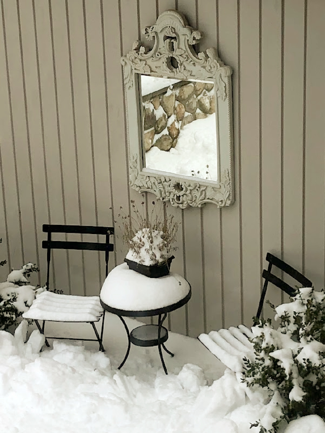 Hello Lovely's snowy French country courtyard with bistro set and ornate mirror. #hellolovelychristmas