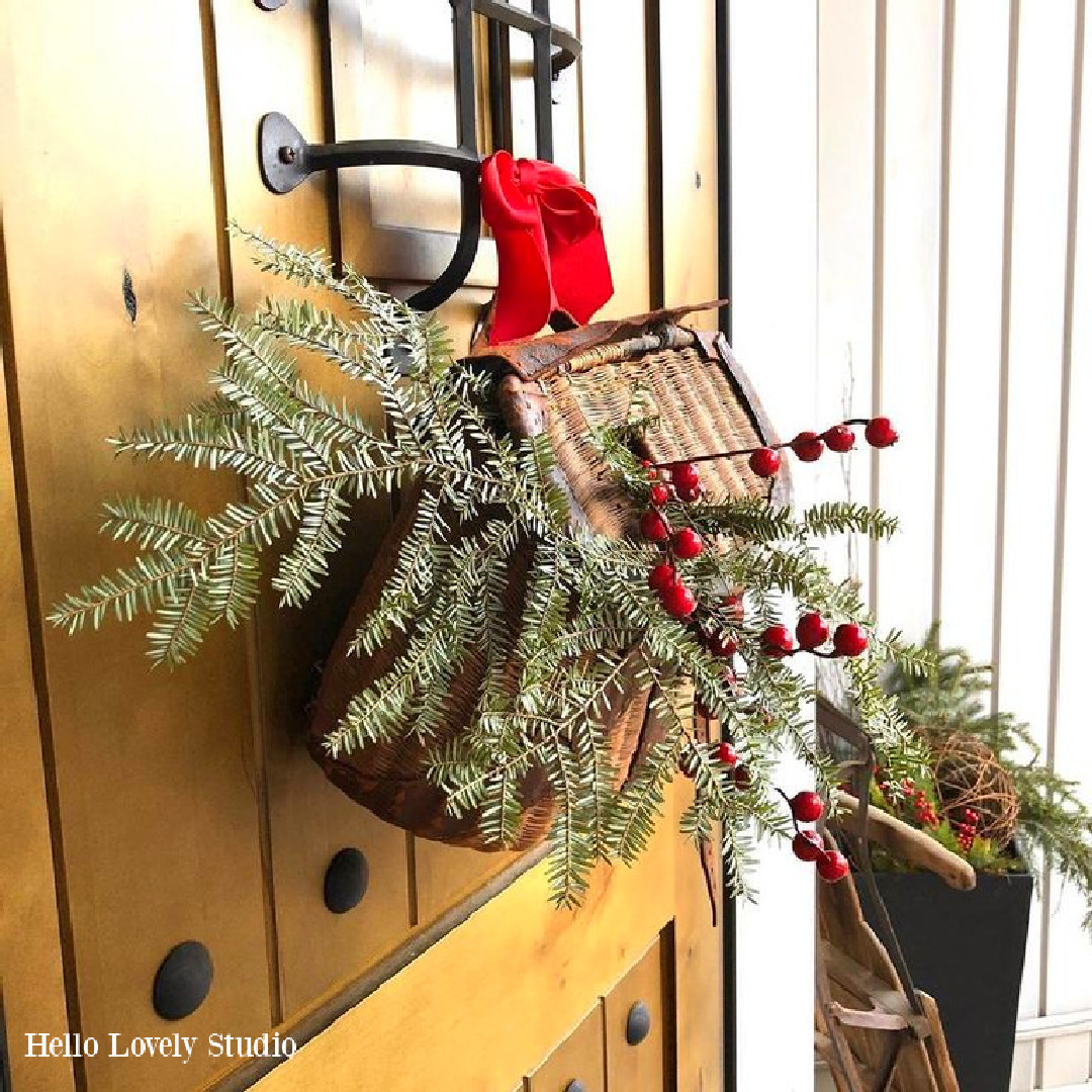 Vintage fishing basket with fresh greenery for Christmas door and front porch - Hello Lovely. #rusticchristmas #christmasdoor #hellolovelychristmas