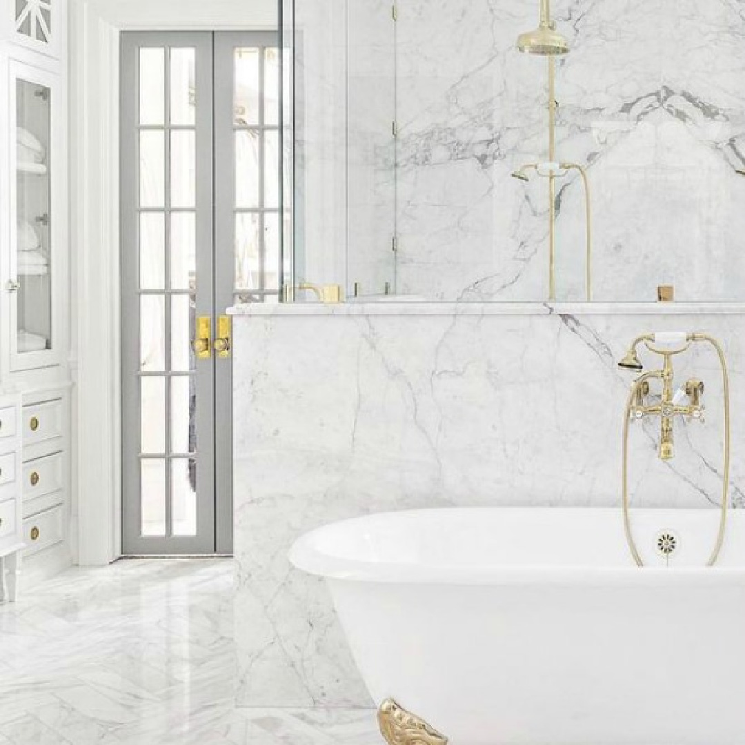 The Fox Group - luxurious white marble bath with light gray French doors and gold toned hardware. #whitemarblebath #bathroomdesign