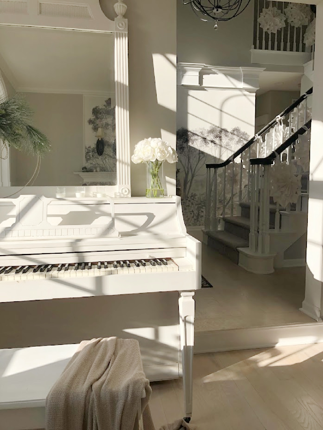 Hello Lovely white Christmas 2024 with snowflake garland on stairs and white piano in dining room. #hellolovelyhome