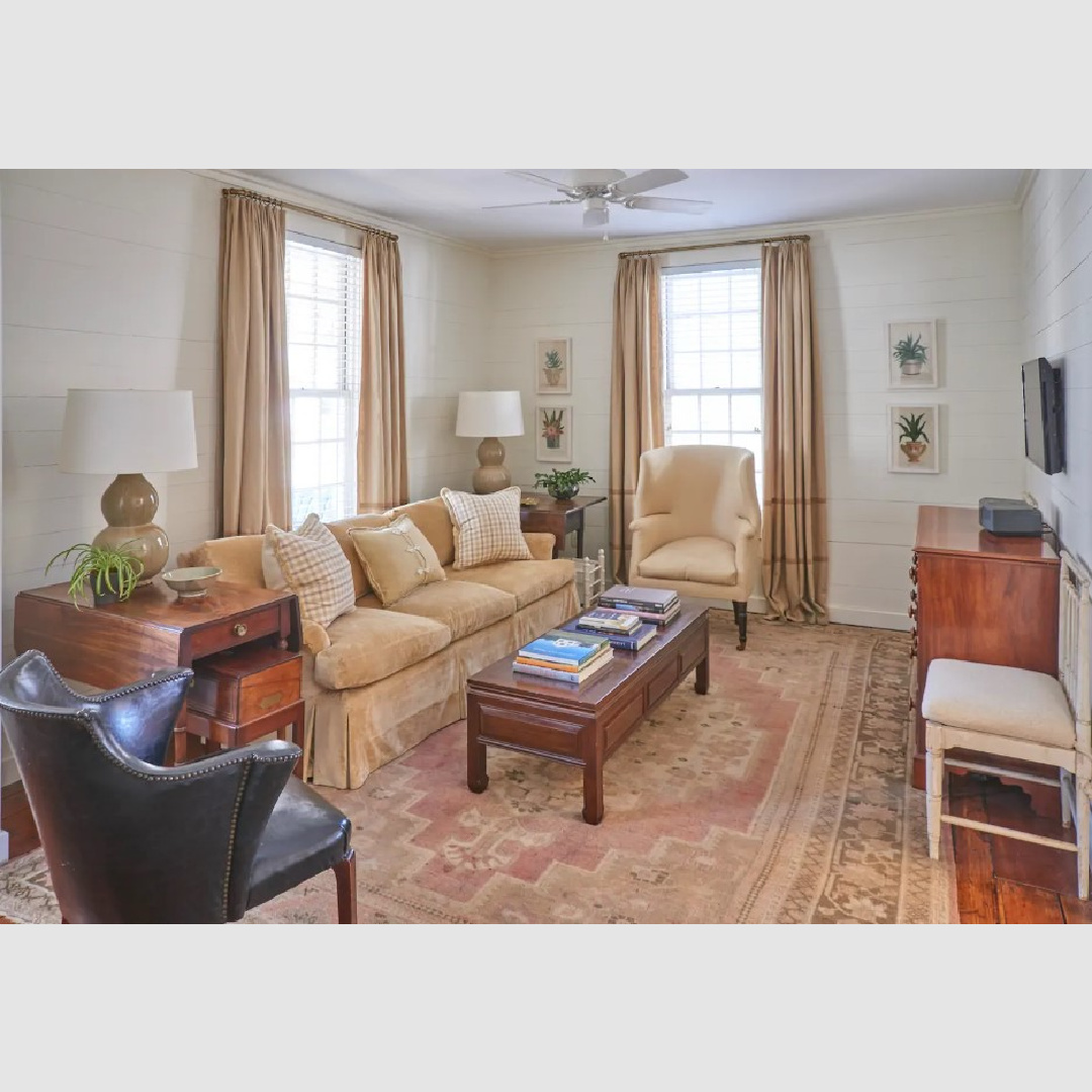 Barefoot elegance in a lovely Southern cottage living room with shiplap, sumptuous velvet sofa and rosy tones on area rug. Southern Living.