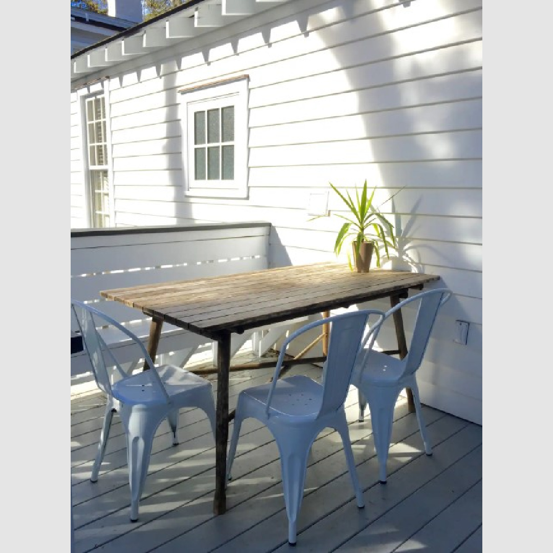 Back deck of a tiny southern cottage with metal industrial Tolix chairs and wood table - Southern Living.
