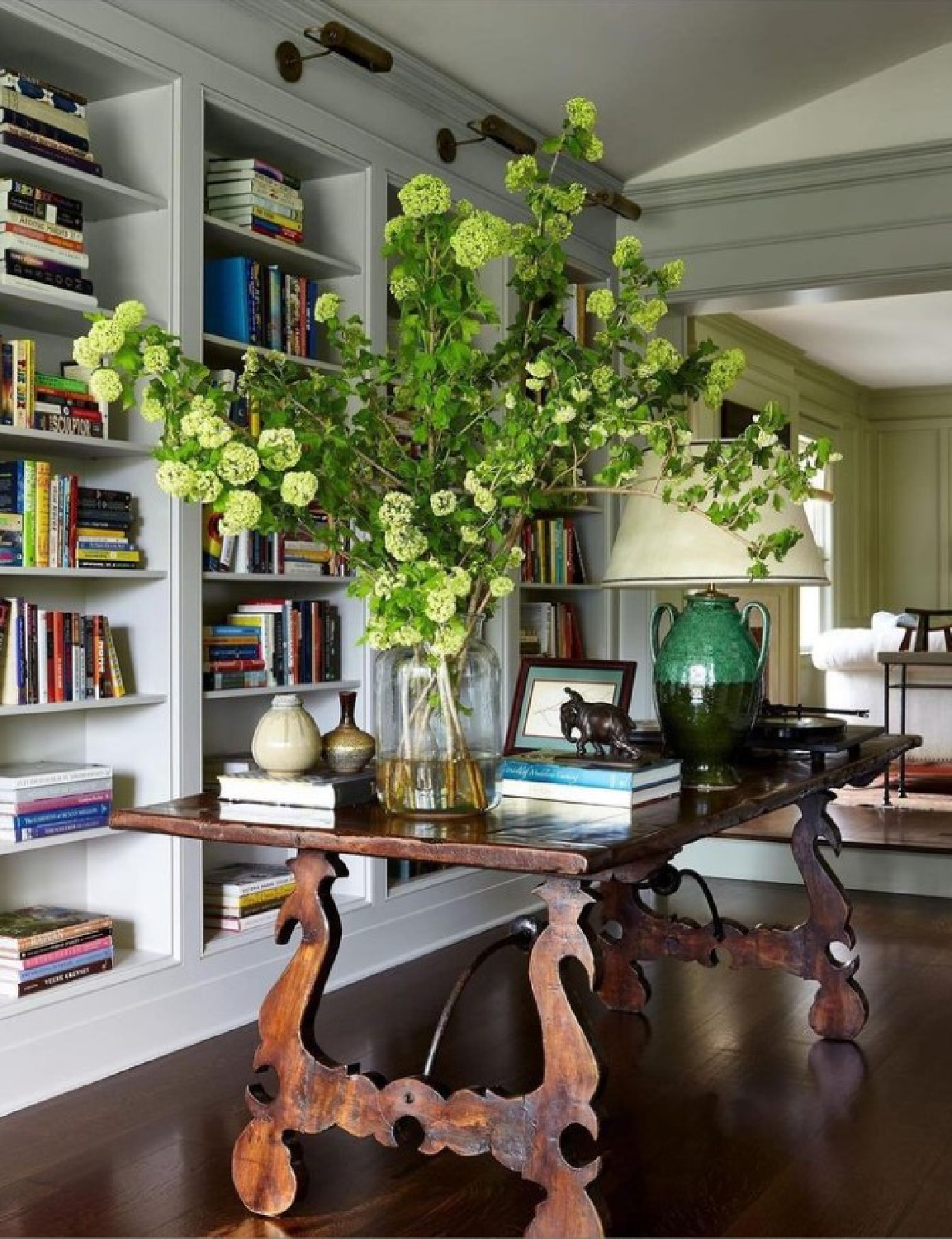 Beautiful antique library table with a dramatic snowball tree stem - @mcgrath2. #homelibrary #librarytables