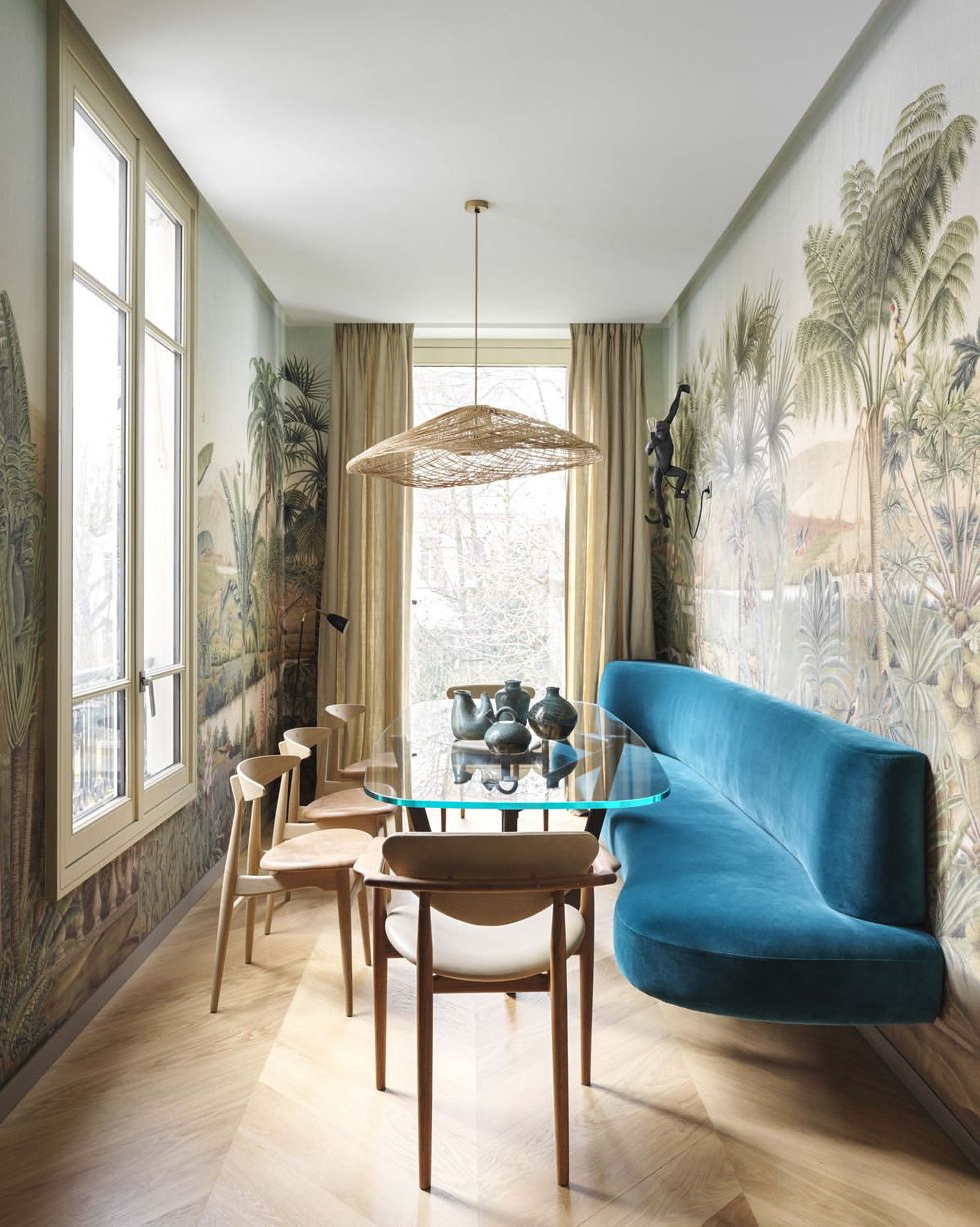 Chic curvy teal velvet built-in floating banquette and scenic tropical wallpaper in a chic dining room by Raphael Le Bree and Thomas Vevaud in Veranda.
