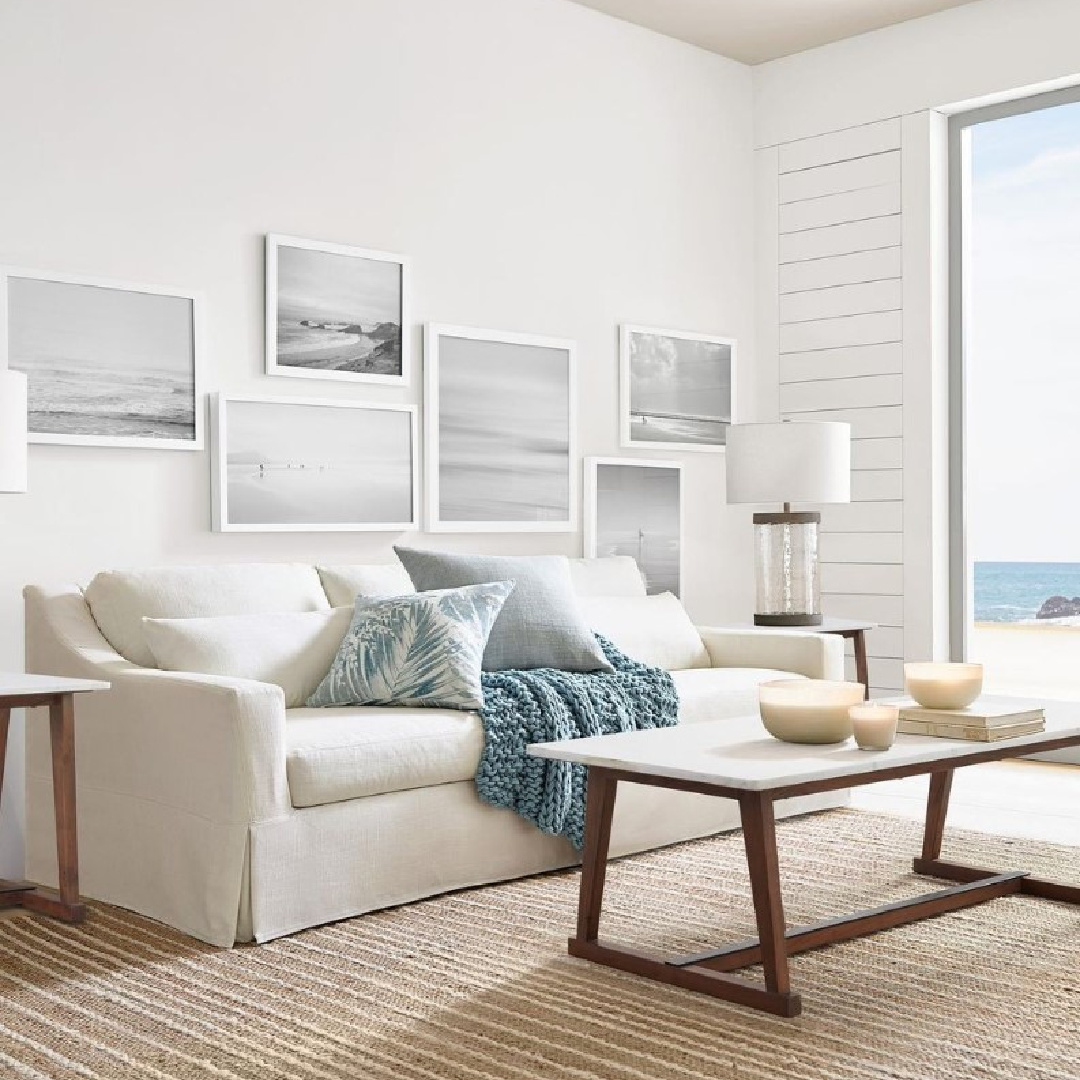 Sherwin Williams Pure White painted seaside living room with gallery wall and Belgian linen sofa - Pottery Barn. #sherwinwilliamspurewhite #coastallivingroom