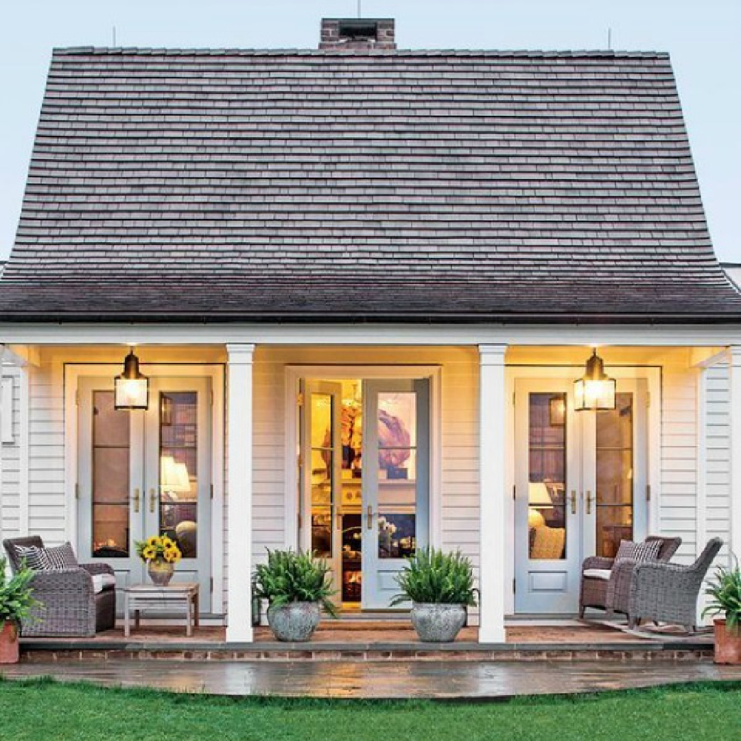 Small white cottage with three sets of French doors and wide country porch - Lucy Williams Interiors. #southerncottages #lowcountrycottage #countryfrontporch