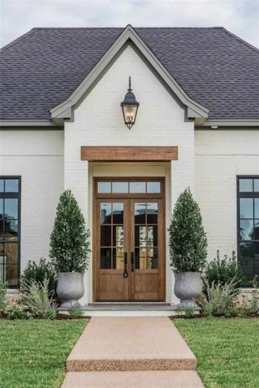 SW Dover White painted brick house exterior with natural wood double door entrance - AACMM via Magnolia Homes. #sherwinwilliamsdoverwhite #whitebrickhouses #whitebrickpaint