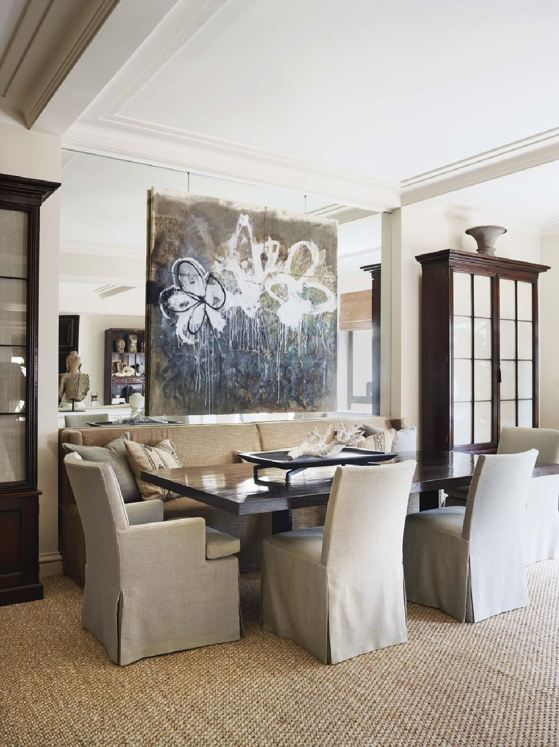 Dining room flanked by glass door cabinets with banquette, mirror, and painting hung on mirror - Thomas Hamel in Veranda.