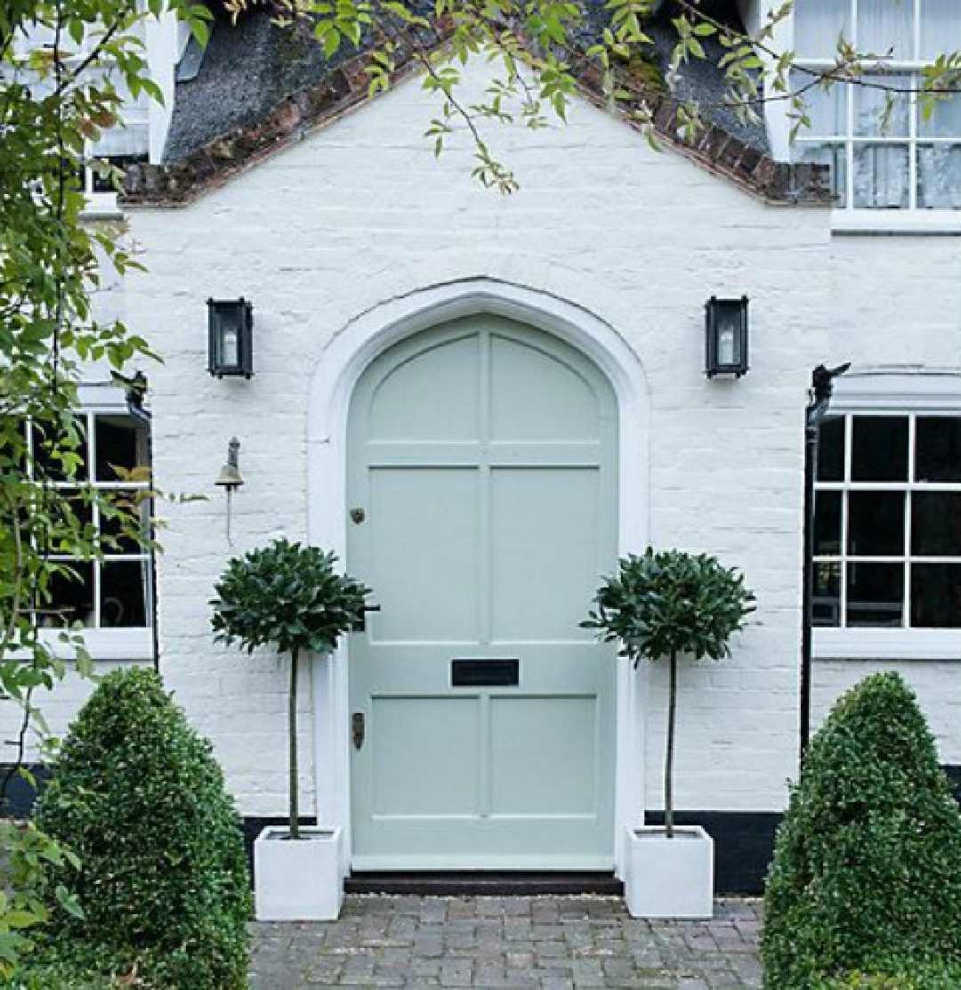 White brick painted English cottage with gray-green door (reminds me of BM Greyhound) and potted Sweet Bay Trees - Thompson Morgan. #whitebrickhouse #englishcottages #whitecottages
