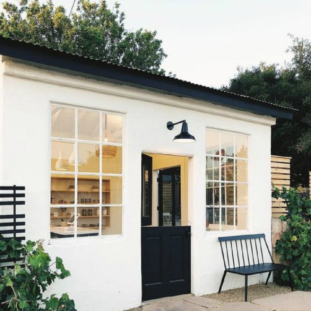 Try a white such as BM Chantilly Lace or Farrow & Ball All White for this look. Small white shop or studio with black Dutch door and farmhouse bench - via Schoolhouse.