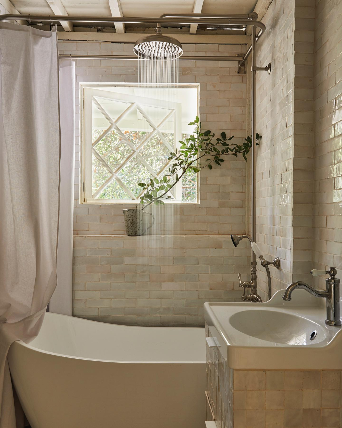 Leanne Ford designed tonal bathroom with tumbled beige tile and soaking tub.