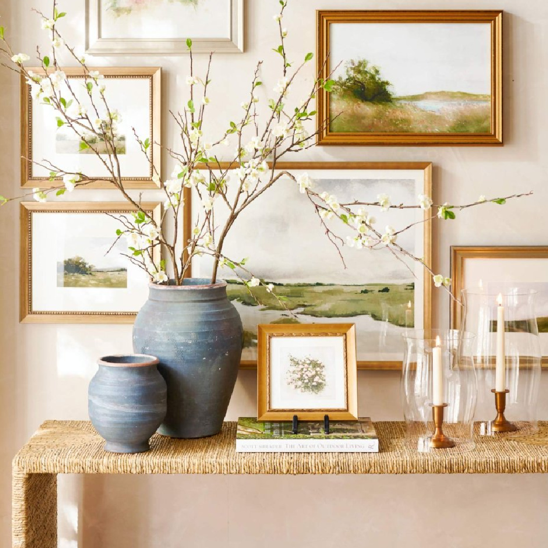 Gallery wall with framed art in soft spring colors above console table, Pottery Barn.