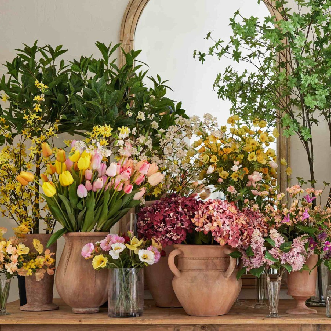 Spring blooms in massed arrangement on console with arched mirrors, Pottery Barn.