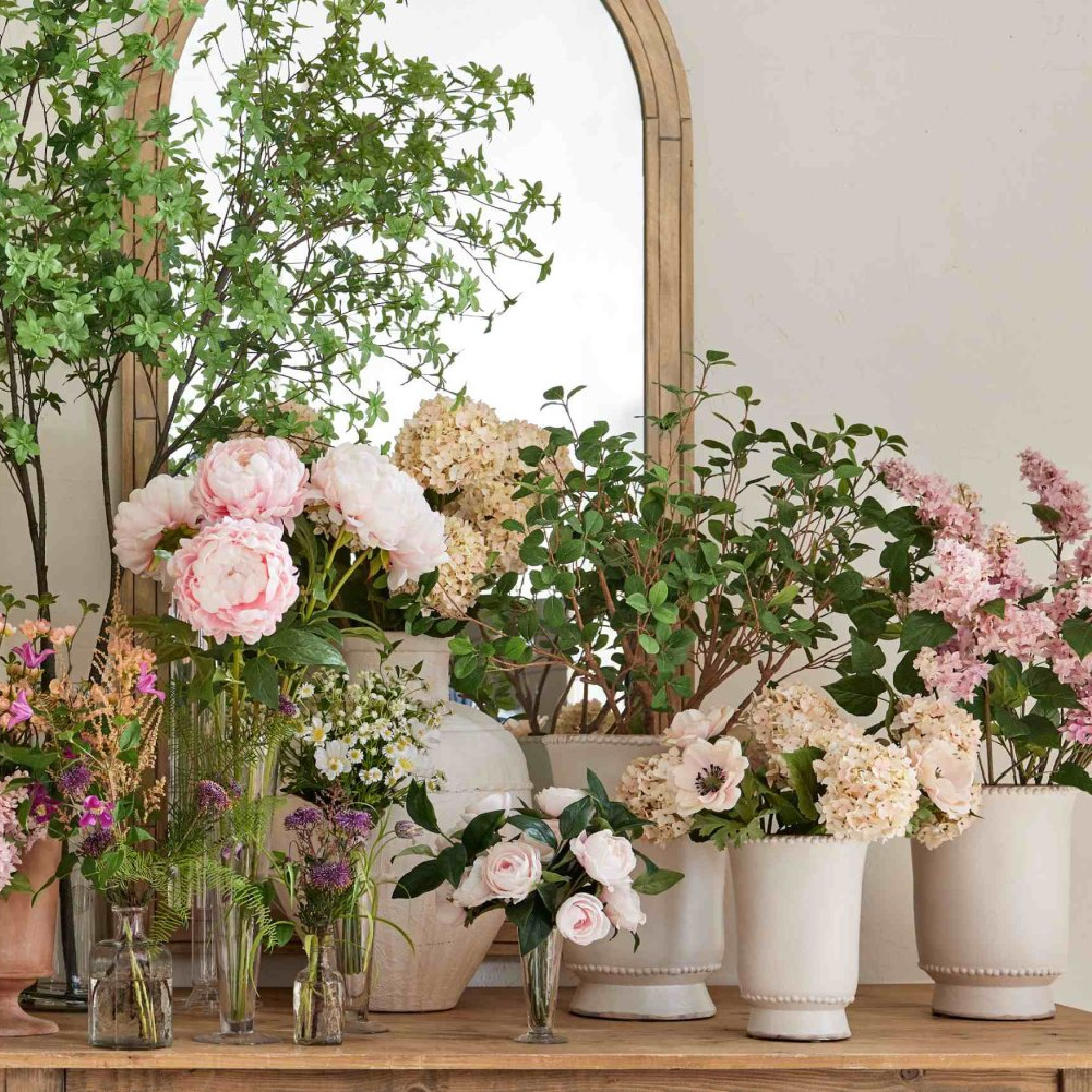 Spring blooms in massed arrangement on console with arched mirrors, Pottery Barn.