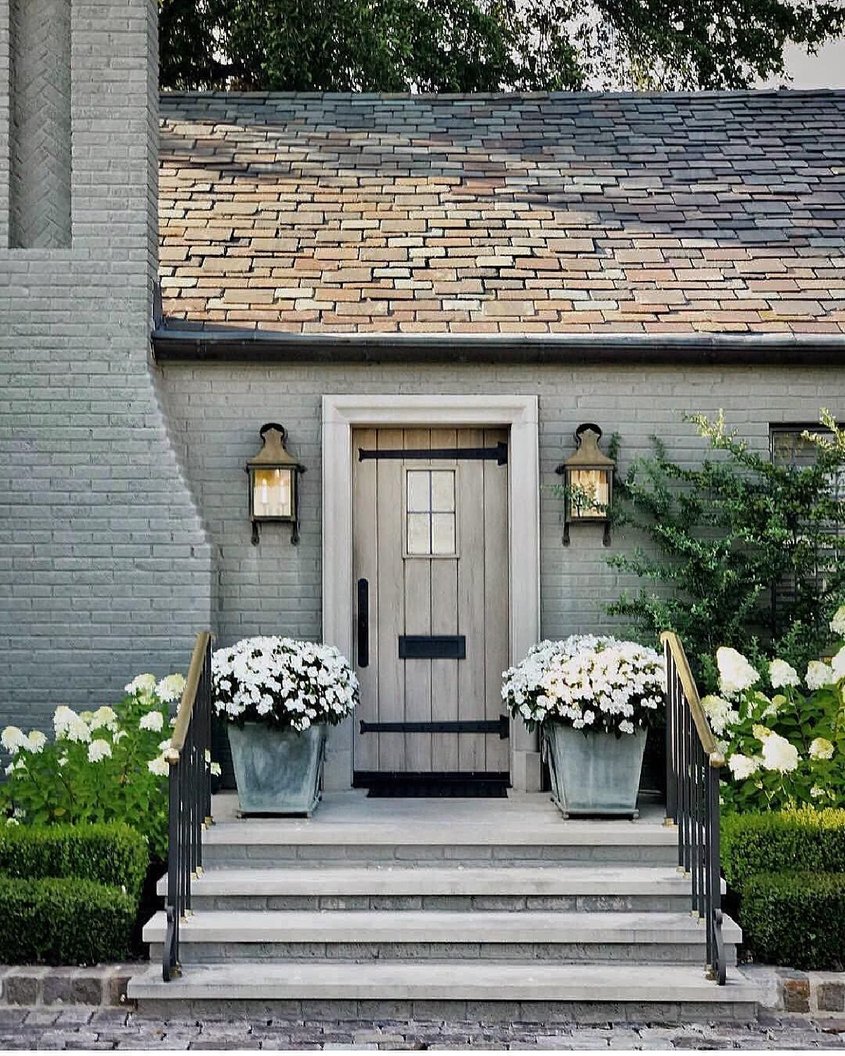 Beautiful painted brick house exterior with charming Old World cottage front door flanked by lanterns. via @jadeexteriors