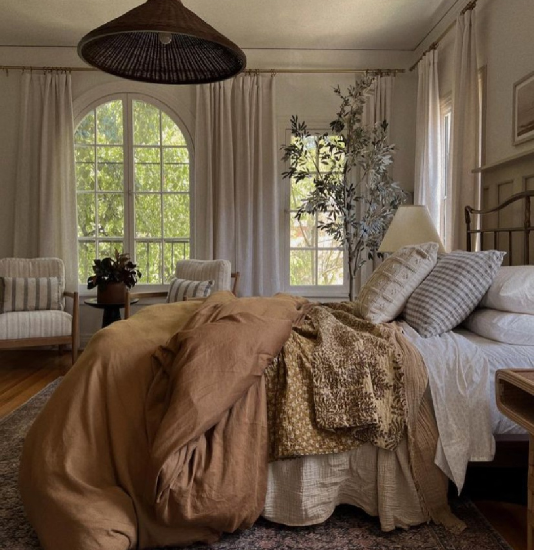 Lonefox designed bedroom with arch windows, modern rustic warmth and earthy goodness from Loloi x Amber Lewis and CB2 rattan pendant.