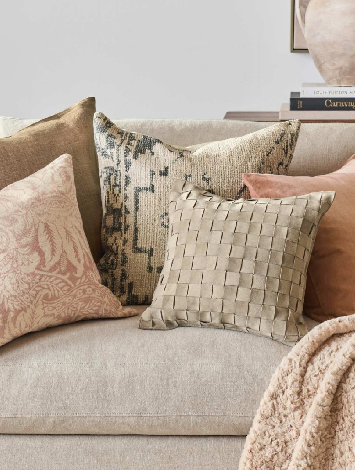 Throw pillows in soft neutrals and rose colors on a sofa, Pottery Barn.