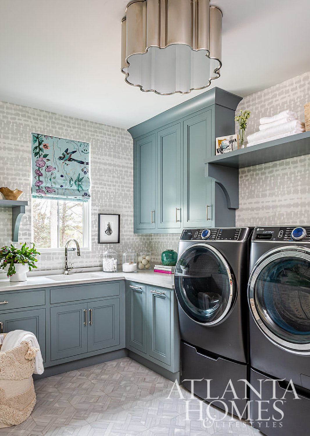 Crystal Corder Interiors designed upstairs laundry with blue cabinetry (Kingdom Woodworks), wallpaper (Phillip Jeffries), and fine art by Holly Irwin (dk Gallery) - AH&L.